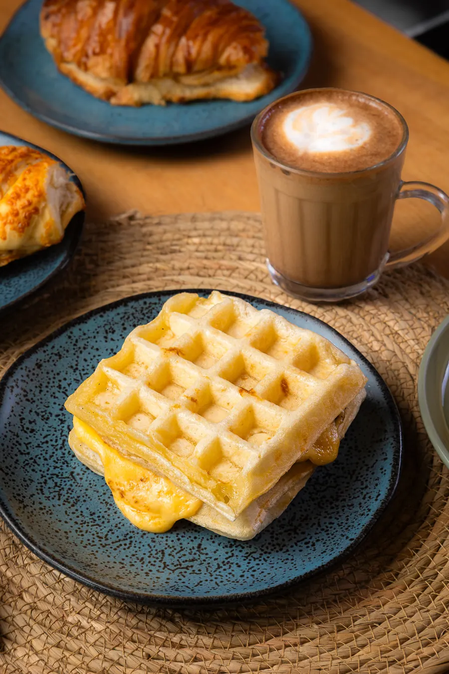 Waffle, croissant e cappuccino com arte no leite
